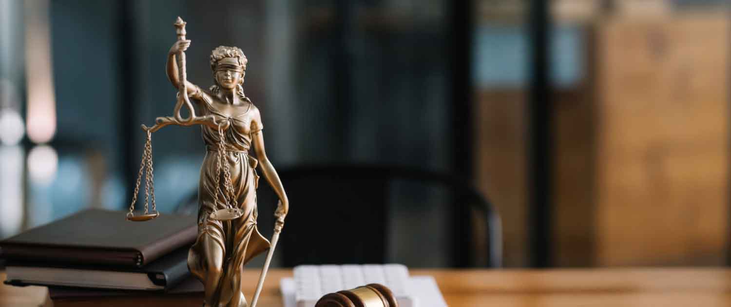 Statue of lady justice on desk next to gavel Statue of lady justice on desk next to gavel
